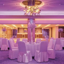 White wedding tables with purple lighting, for a reception at Crowne Plaza Limassol Hotel.
