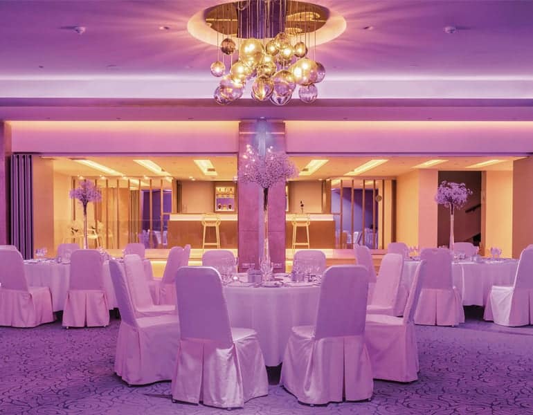 White wedding tables with purple lighting, for a reception at Crowne Plaza Limassol Hotel.