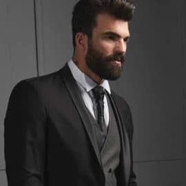 A black suit with a light blue shirt and a black tie worn by a bearded model, by Posh Boutique Cyprus.