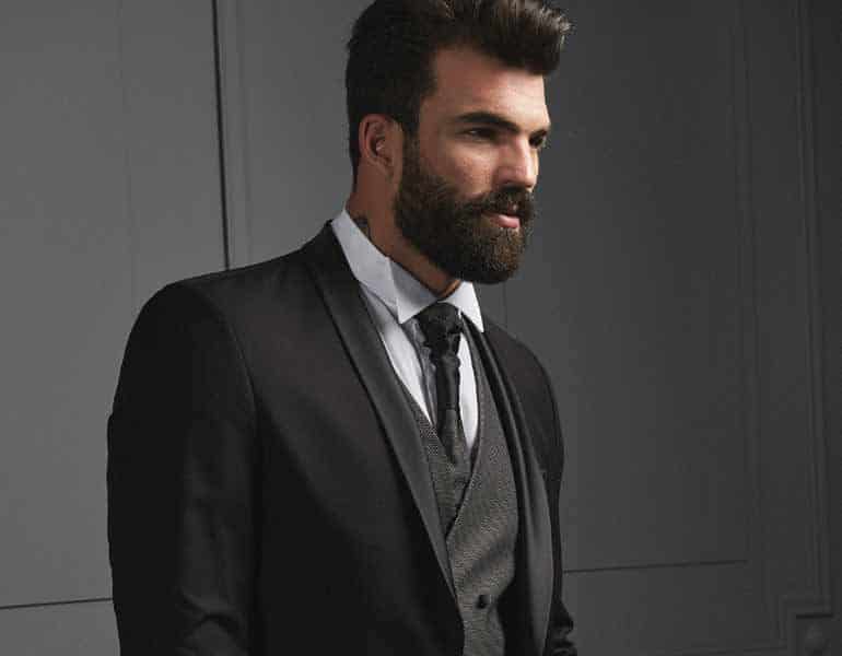 A black suit with a light blue shirt and a black tie worn by a bearded model, by Posh Boutique Cyprus.