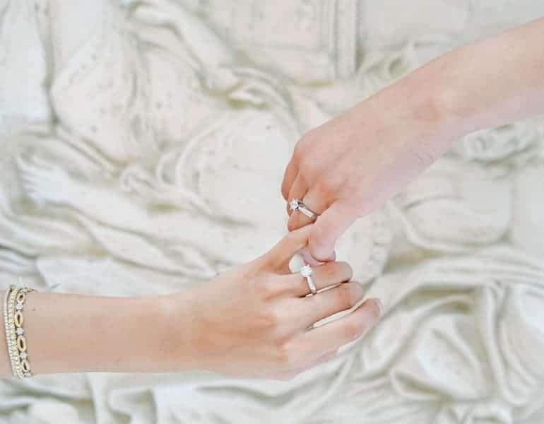Ένα ζευγάρι κράταει χέρια, με βέρες από το κατάστημα Yiotis Jewellery.