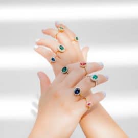 2 hands filled with gemstone rings of different colours, by Yiotis Jewellery in Cyprus.