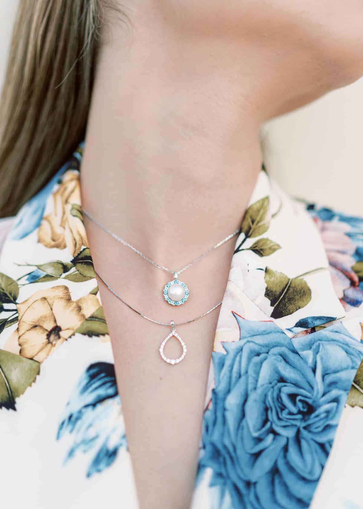 Μια γυναίκα φοράει 2 μενταγιόν, ενά ασημένιο και ένα χρωματιστό, από το Yiotis Jewellery.